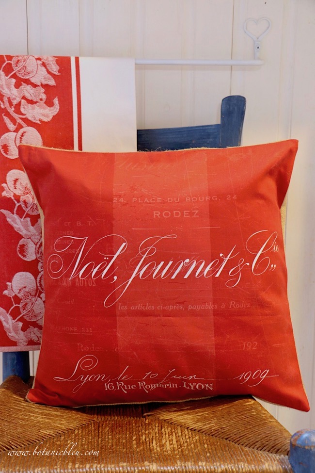 Tone on tone red fabric of a Noël pillow is beautiful shades of red in the French Country Christmas bathroom.