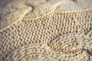 A close-up of a knitted blanket made of off-white yarn.