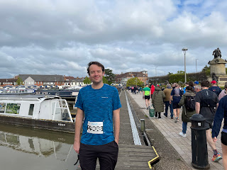 John in front of a canal boat with runners to the right of him walking to the start.