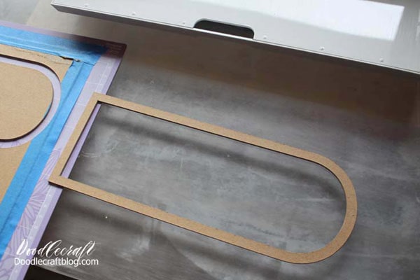Remove from the mat and tape down another chipboard to cut again. Repeat this process until you have 8 chipboard frames cut out.