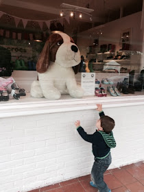 Baby Boy pointing a big toy dog in shop window 