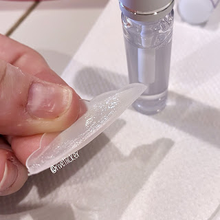 Close up of Lara's thumb holding a lift pad with lash adhesive on it.