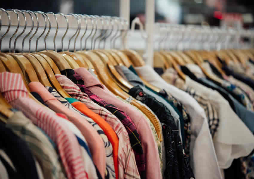 Imagem mostra muitas roupas em uma loja.