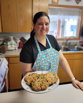 baker offering cookies in a blue apron