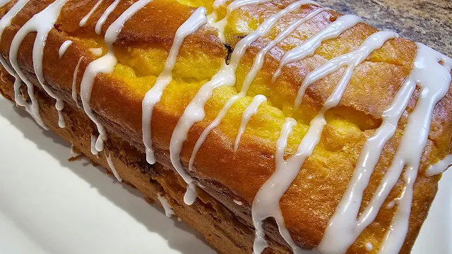 A loaf of lemon blueberry snack cake with icing drizzled over the top.