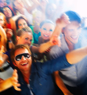 Man with white rimmed sunglasses surrounded by happy people