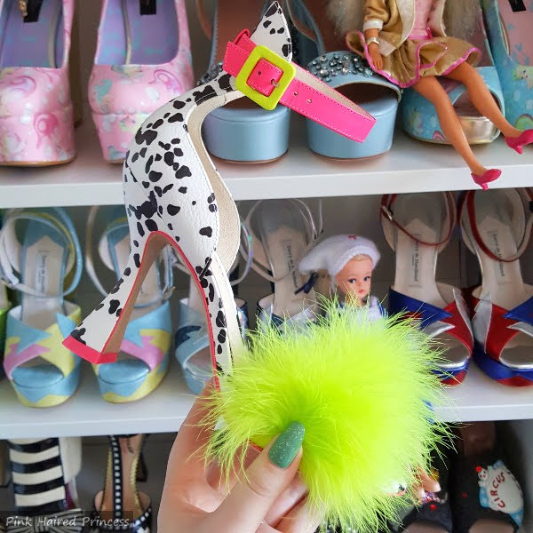 dalmatian print sandal with fluffy front held in hand with shoe shelves in background