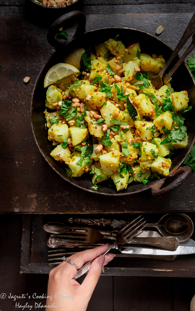 Potato and peanut farali bhaji in a kadai with roasted peanuts, coriander and lemon wedge.