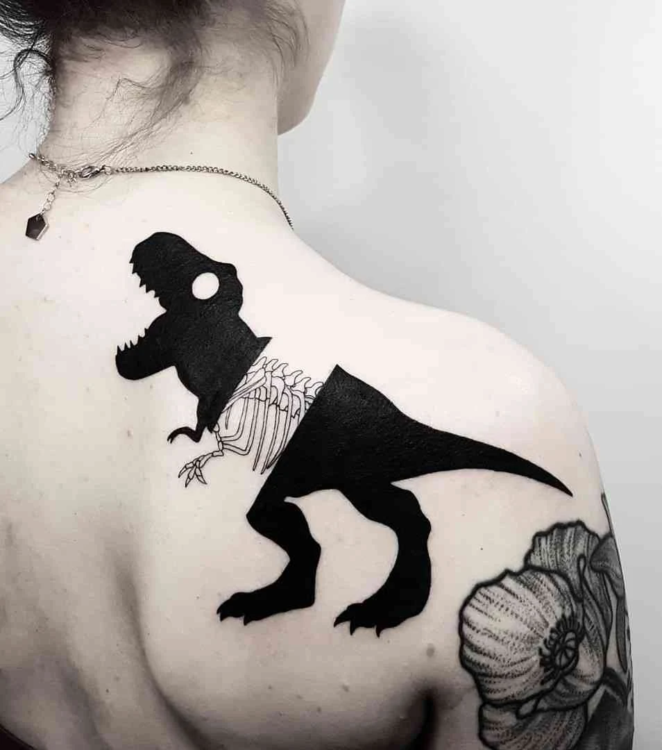 Vemos un tatuaje en blanco y negro de tiranosaurio