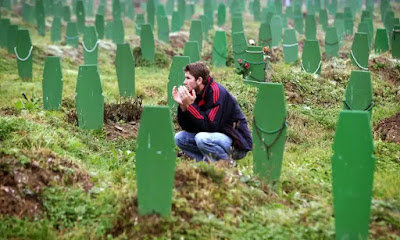 Photo courtesy guardian.co.uk: man praying at the gravesites of Srebenica