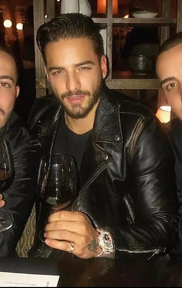 Handsome man wearing black leather biker jacket holding a wine glass with friends on either side