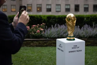 Troféu da Copa do Mundo exibido em um evento, reluzindo sob as luzes e simbolizando a busca pela vitória no futebol.