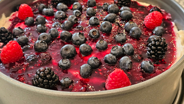 A no bake mixed berry cheesecake topped with blueberries, raspberries, and blackberries in a springform pan.