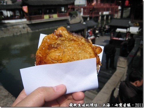 拿到「海棠糕」準備大快朵頤了，還燙著呢！所以要用紙拿著，外皮是烤過的，就像我們的車輪餅拿去烤過一樣。