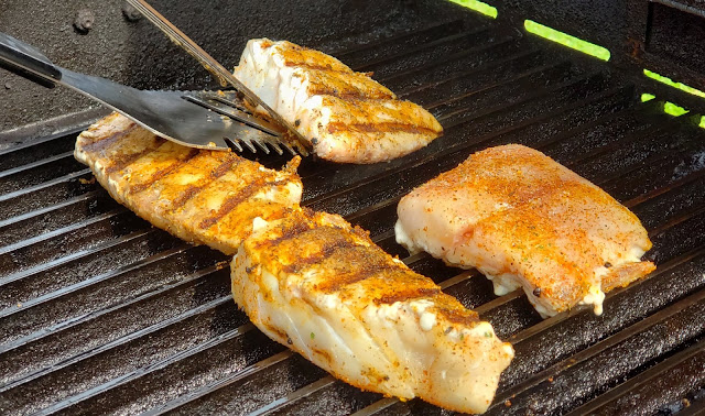 Four pieces of red snapper cooking on a grill.