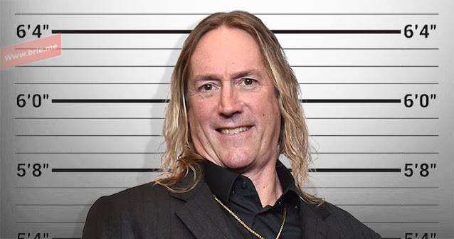 Danny Carey posing in front of a height chart background