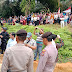 Spanduk Bertuliskan "Tegakkan Keadilan" Terbentang  Ditengah Kerumunan Ratusan Masyarakat Saat Menyaksikan Sidang Lapangan Terkait Kematian Paino.