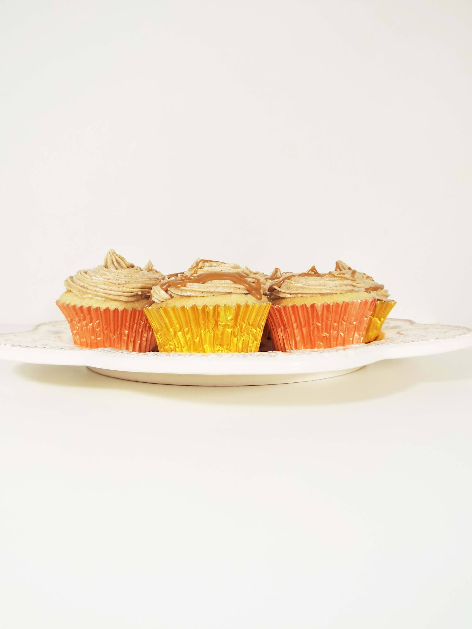 Biscoff cupcakes wrapped in gold and copper cases, displayed on a cake plate.
