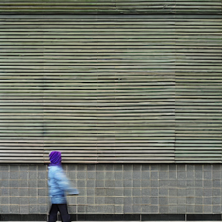 Ein Kind geht an einer Häuserfassade vorbei und die Mauer wirkt wie ein Barcode