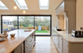 bespoke open plan kitchen diner with bifold doors, Carrara marble and solid oak worktops, farrow and ball Manor House grey and downpipe units, island, integrated appliances, pendant lighting and statement extractor hob. shaker style kitchen inspiration.