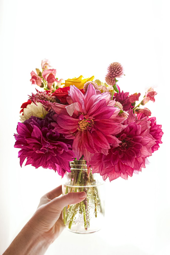 Jar brimming with spring blooms held by the photographer as a sort of self portrait