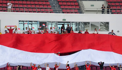 Suporter membentangkan bendera merah putih raksasa ketika menyaksikan pertandingan