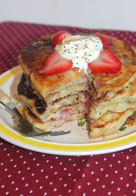 Cutting into a stack of strawberry sour cream poppy seed pancakes.