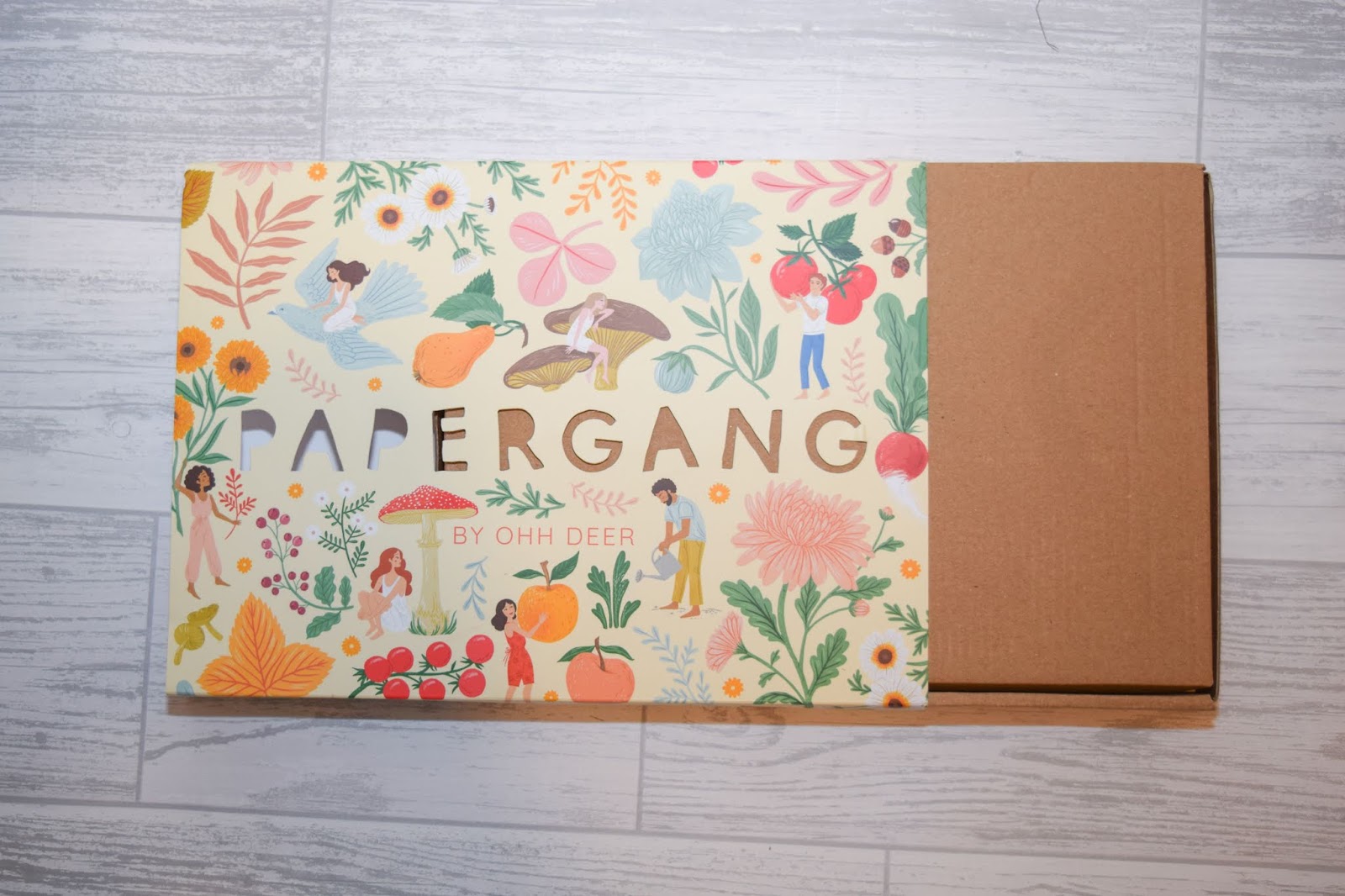 A box sleeve half pulled away with a vegetable and wildflower print on the front.