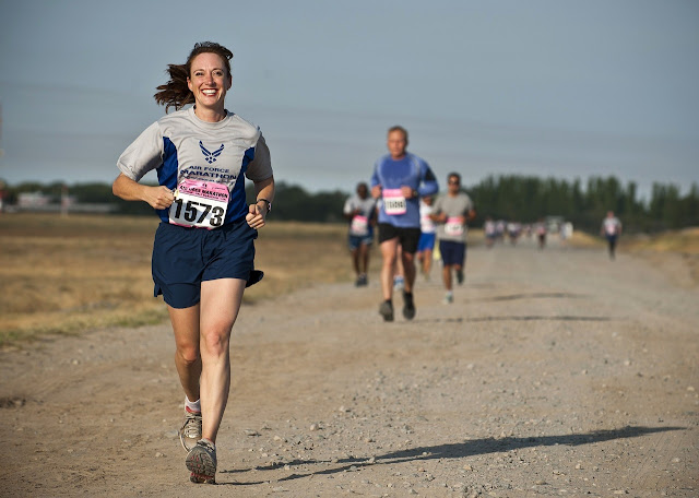 Woman running on dirt path, smiling and happy