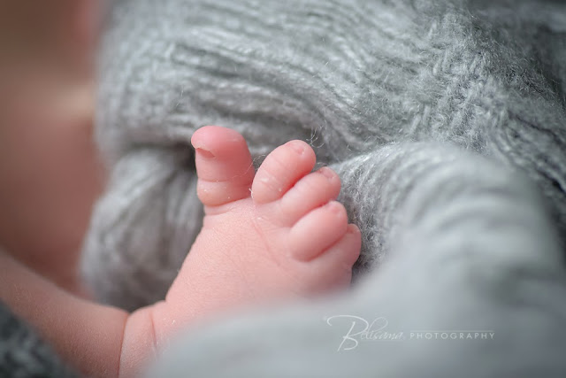 close-up shot of newborn baby feet on grey blanket 