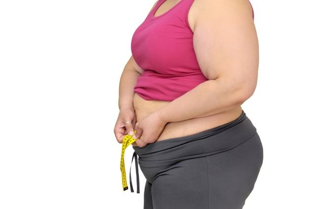 a woman measuring her belly fat