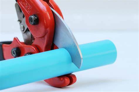 A PVC pipe cutter, blades encircling a blue pipe