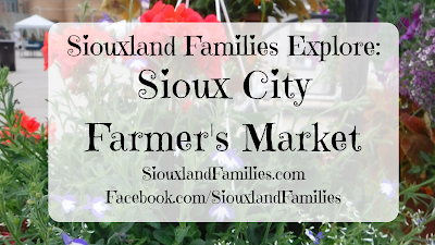 in background, red and purple flowers drape over a hanging basket at the Sioux City Farmer's Market. In foreground, the words "Siouxland Families Explore: Sioux City Farmer's Market"