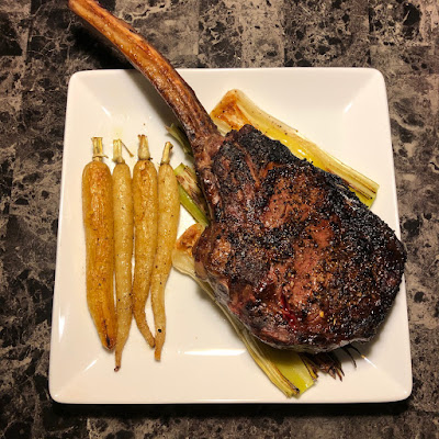 Rare grilled tomahawk ribeye with grilled leeks and white carrots