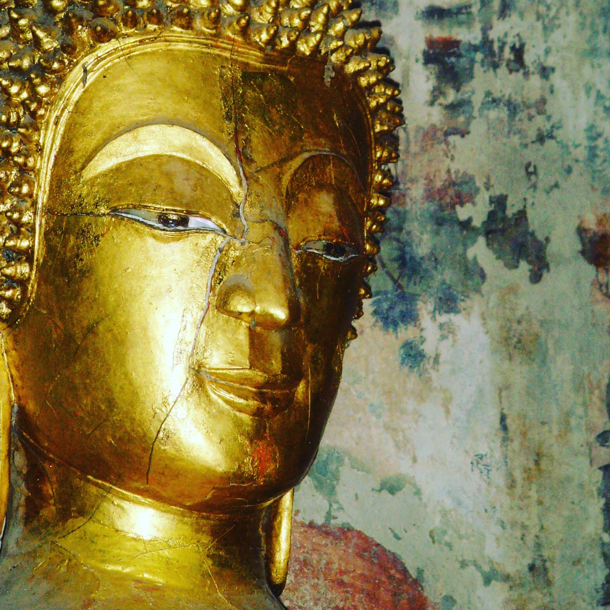 golden buddha head against old wall in laos