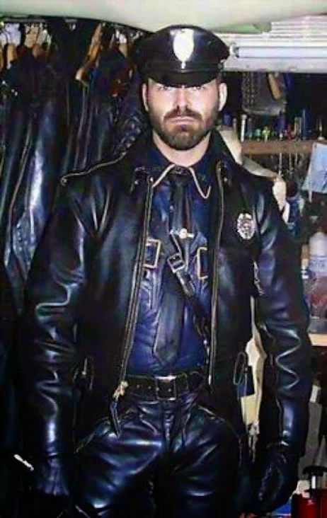 Leathermen Master wearing smooth black gear in a closet full of leather clothing