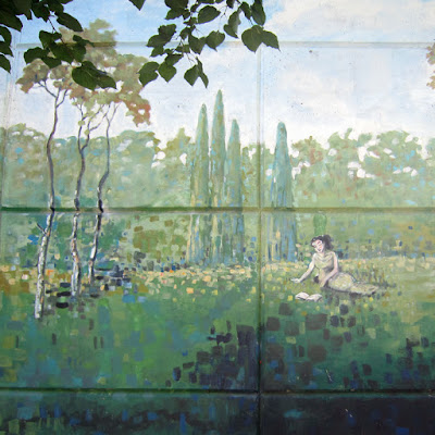 Photo of a detail from an Ian Leventhal mural showing a woman sitting outside on the grass reading a book
