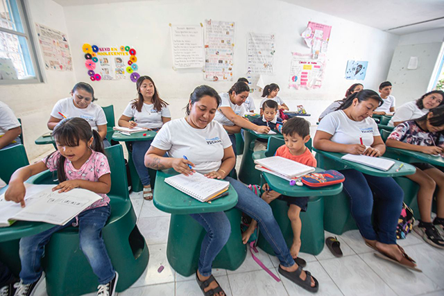 Una ama de casa hace su tarea escolar mientras atiende las de su hijo en el mismo salón