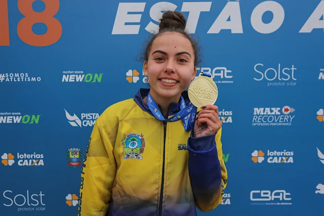 Helena mostra uma medalha de ouro para fotos