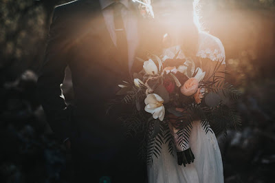 Novios en un jardín en zona y de sombra e iluminados por un rayo de sol