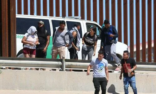 Venezuelan nationals walk along the border fence to a waiting Border Patrol van after illegally crossing the Rio Grande from Mexico, in El Paso, Texas, on Sept. 21, 2022.