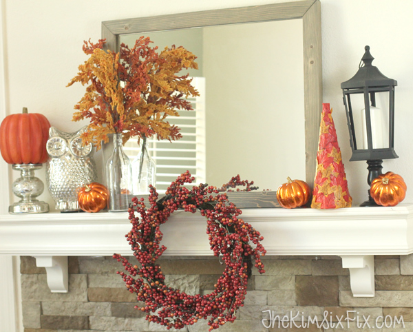 A gorgeous fall mantel in oranges and reds with accent pops of silver and black.  I love how the wreath is hung off the front of the mantel shelf! 