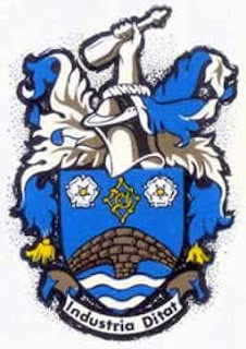 Knottingley's coat of arms. Arms: Azure issuant from Water barry wavy in base a Bridge of two arches proper in chief a Lacy Knot Or between two Roses Argent barbed and seeded also proper. Crest: On a Wreath Argent and Azure a cubit Arm holding an ancient Glass Bottle proper. Motto: industria didat - progress through industry