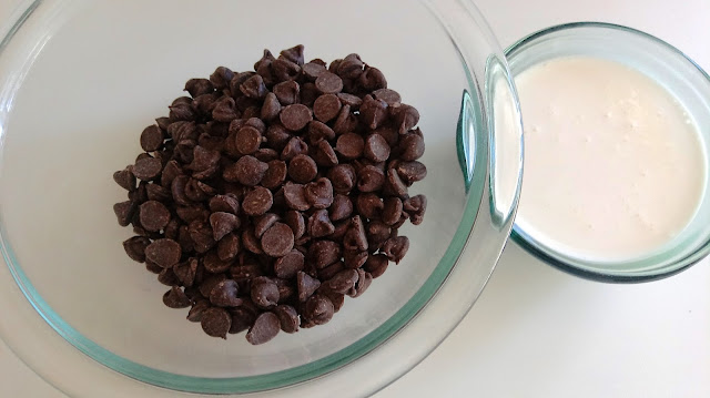 a bowl of chocolate chips next to a small bowl of cream