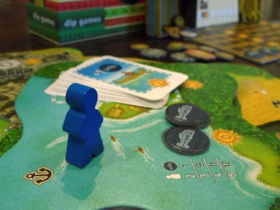 Blue player board game meeple and Altiplano shoreline location board with fish and canoes