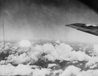 A black and white photograph of clouds from a plane window.