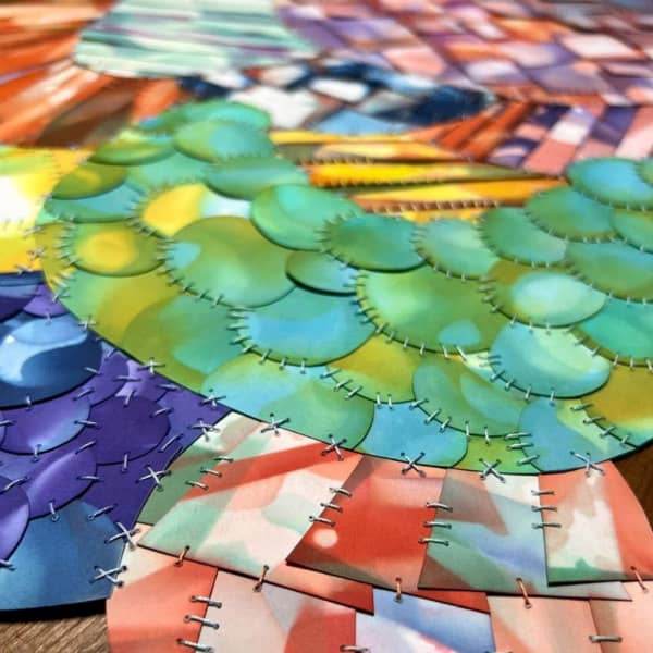 detail of multicolor, stitched paper quilt composed of circular and rectangular shapes