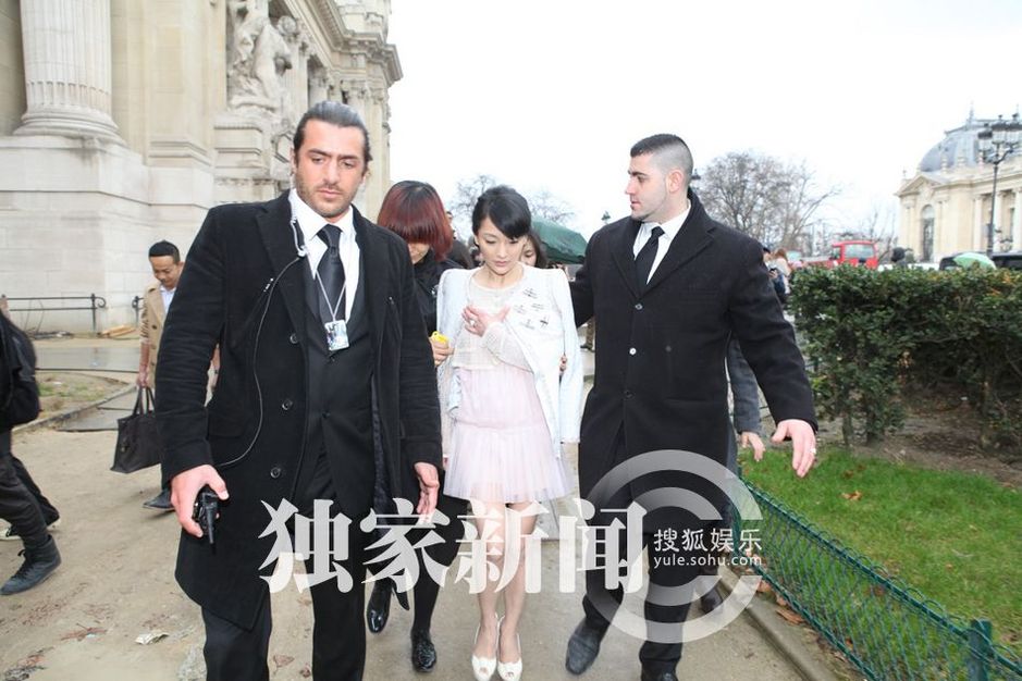 Burly but stylish security men escort the diminutive Zhou Xun to her next
