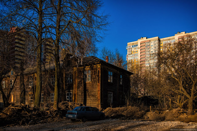 Припаркованная машина у руинированного деревянного дома