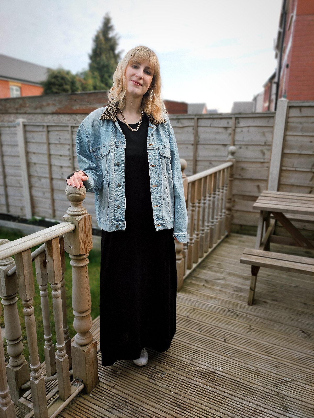 Outfit photo (outdoor, in garden), wearing a long black maxi dress and a denim jacket with a leopard print collar.